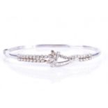 An 18ct white gold and diamond banglethe stylised asymmetric mount inset with round and baguette-cut