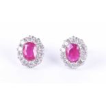 A pair of 18ct white gold, diamond, and ruby cluster earringseach set with a mixed oval-cut ruby