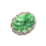 An 18ct white gold jade and diamond brooch, the central piece of carved jade surrounded by diamonds.