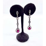 A pair of 18ct white gold ruby and diamond drop earrings, each earring set with a pear shape claw