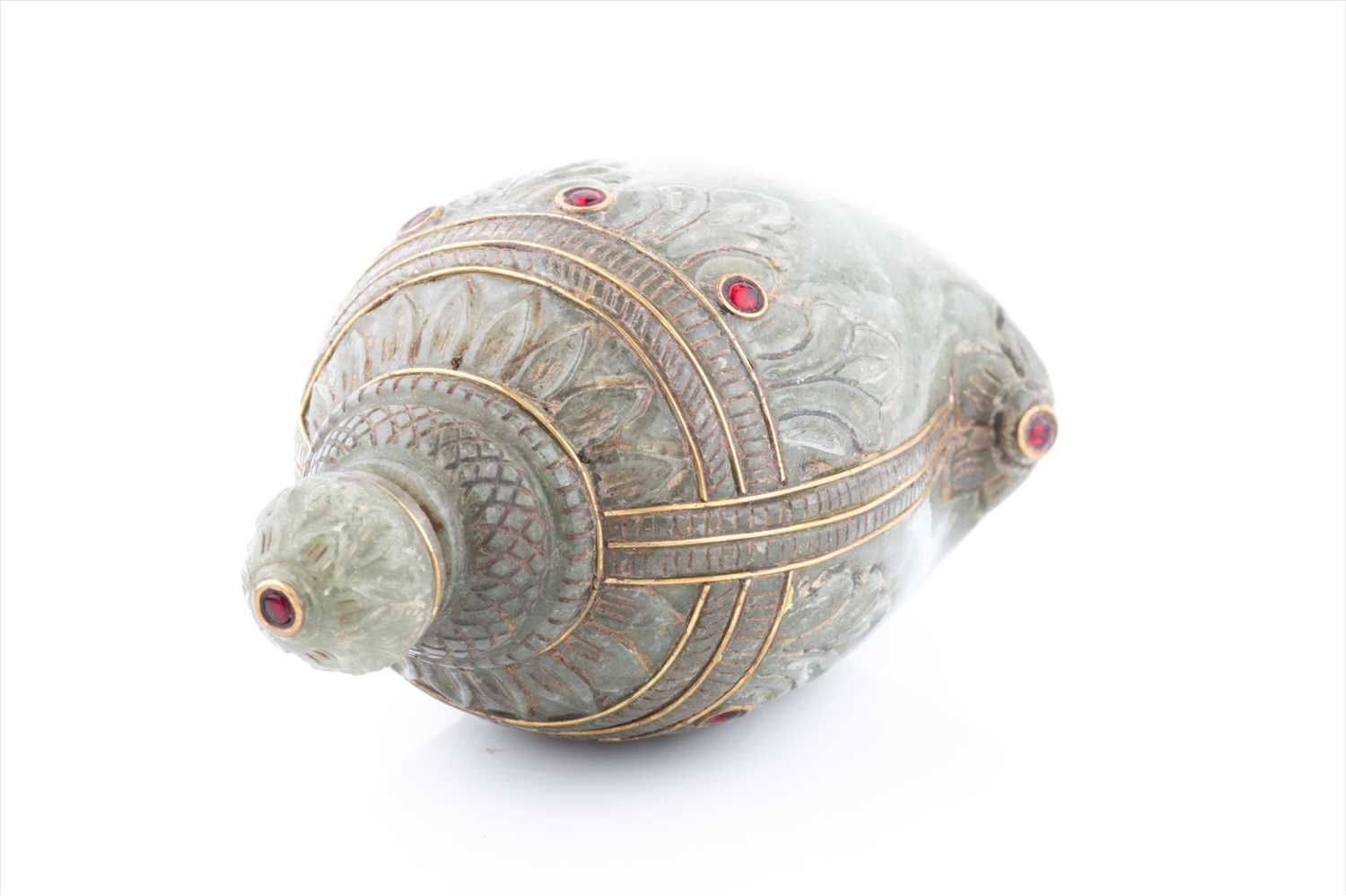 A Mughal style celadon jade scent bottle, of conch form with carved acanthus, red paste bejewelled