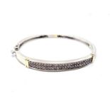 A 14ct two colour diamond bangle. 50 claw set diamonds weighing a total of approximately 1.00 carat.