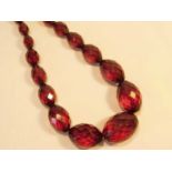 A string of faceted olive shaped graduated amber beads, the largest bead 23mm wide x 16mm Overall