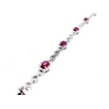 An 18ct white gold ruby and diamond bracelet, set with seven oval rubies of good colour weighing a