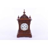 A late 19th century oak mantel clock, the white enamel dial with black Roman numerals, striking on a