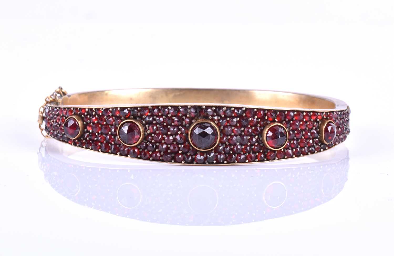A late Victorian garnet bracelet, the gilt metal hinged bangle set with five collet-set rose-cut