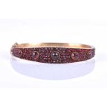 A late Victorian garnet bracelet, the gilt metal hinged bangle set with five collet-set rose-cut