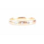 An 18ct yellow gold and diamond band ringthe band inset with three diamond accents, hallmarked