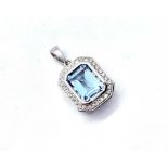 A 9ct white gold blue topaz and diamond pendant, the central rubover set blue topaz weighing 2.