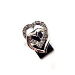A 9ct white gold diamond heart ring. 20 claw set brilliant cut diamonds of tinted colour and SI