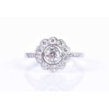 A platinum and diamond floral cluster ringcentered with a collet-set round brilliant-cut diamond,