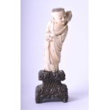 A Chinese carved ivory figure of a young monk, 19th century, well carved holding the stems of a