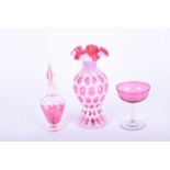 A Fenton cranberry and white overlay glass vase, with frilled rim above round and oval panels, a