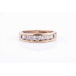 A yellow metal and diamond ring, the channel-set band with seven round briliant-cut diamonds,
