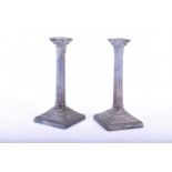 A pair of Georgian style silver candlesticks, 20th century, Sheffield, with composite capitals above