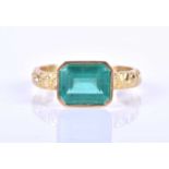 An 18ct yellow gold and emerald ring, the emerald-cut emerald set east to west in a bezel mount, the