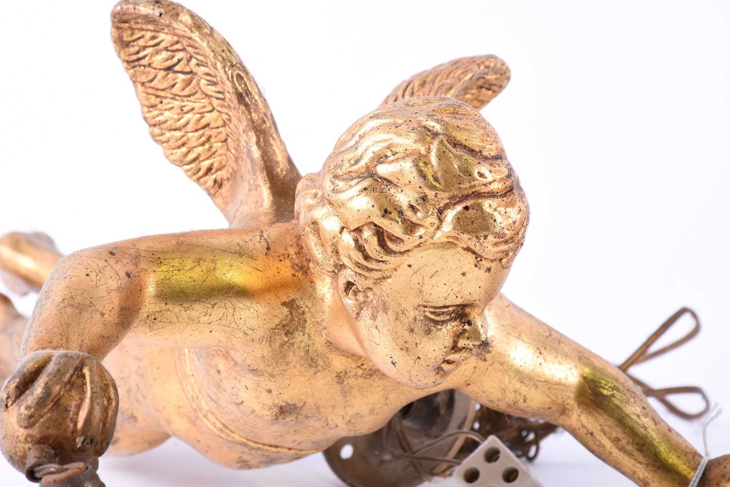 Two mid-20th century ceiling light pendantsmodelled as gilt putti, holding suspended lamp holders in - Image 3 of 4