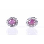 A pair of diamond and ruby cluster earringseach centred with a star ruby showing six-point asterism,