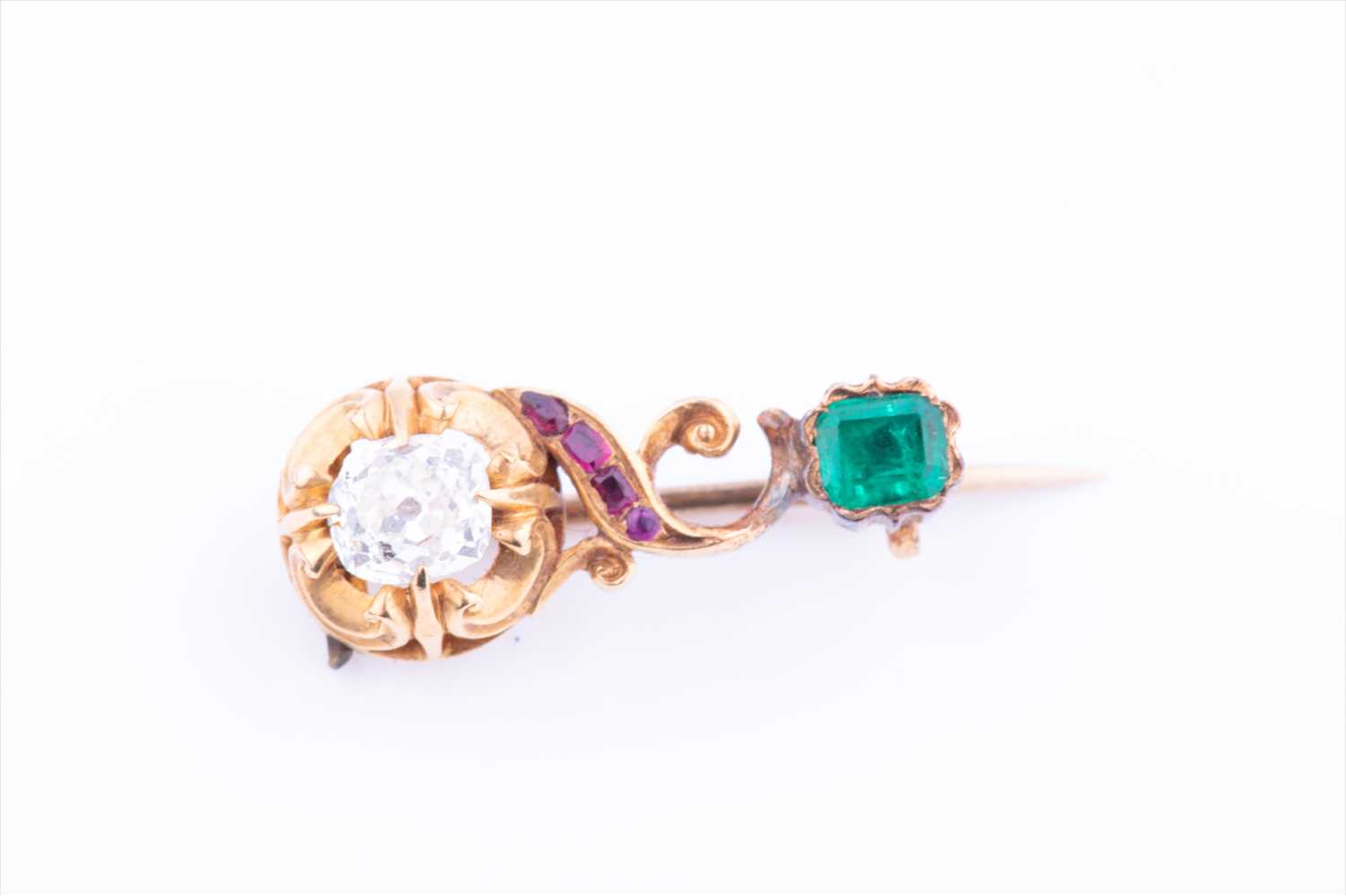 A charming late 19th century yellow gold, diamond, ruby, and emerald broochof swirled bar design,