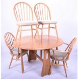 An Ercol blonde elm drop-flap oval dining table together with four conforming Windsor-style Ercol