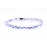 An 18ct white gold, diamond, and tanzanite line braceletset with mixed oval-cut tanzanites