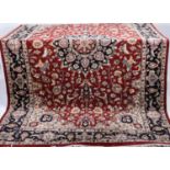 A large 20th century Persian room carpet decorated throughout with foliate motifs on a red ground,