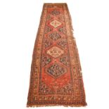 A Persian red & blue ground runner, with hooked guls within decorative band borders, 378 x