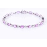 An 18ct white gold, diamond, and pink sapphire line braceletset with mixed oval-cut sapphires of