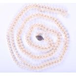 An opera length pearl necklace,comprised of cultured pearls, fastened with a yellow metal, white and