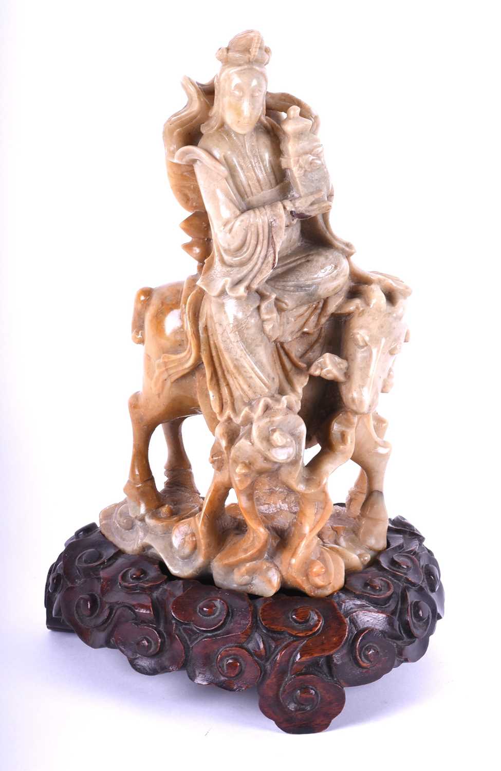 A Chinese carved soapstone figure of Guan Yin, late Qing, carved holding a vase and seated upon a