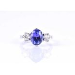 A diamond and tanzanite three-stone ringcentred with a mixed oval-cut tanzanite of approximately 2.