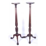 A near pair of mahogany torcheres, 19th century, each with reeded inverted tapering columns, on a