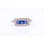 An 18ct white gold, diamond, and sapphire ringcentred with three square-cut sapphires, within a