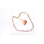 A Chinese carved agate and amber necklace, the agate pendant of brown to white colour, carved with a