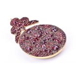 A late 19th / early 20th century yellow metal and garnet pendantof oval form with trefoil surmount