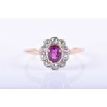 A diamond and ruby cluster ringset with a mixed oval-cut ruby, measuring approximately 5 x 4 mm,