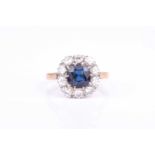 An 18ct yellow gold and sapphire cluster ringcentred with a cushion-cut blue sapphire within a