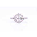 A platinum and diamond ring of hexagonal design, centred with a round brilliant-cut diamond within a