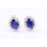 A pair of diamond and sapphire earringseach set with a mixed oval-cut sapphire, within a border of