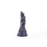 A 19th century Wedgwood black basalt figure of a female nude, modelled as a stem holder, seated on a