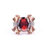 A late Art Deco gold and garnet cocktail ring, set with a mixed-cut garnet, the mount with ornate