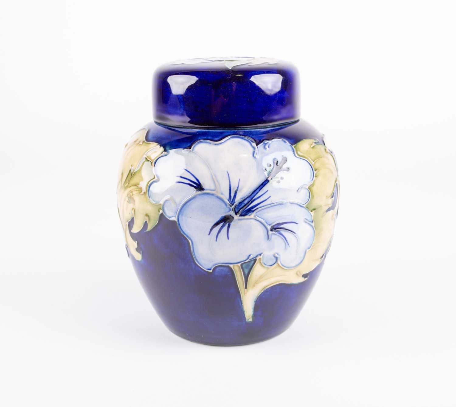 A Moorcroft Hibiscus pattern ginger jar and cover, the pale blue flowers against a dark blue ground,