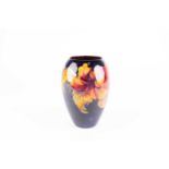A Moorcroft Hibiscus pattern vase, of tapering form, the lustrous red and yellow flowers against a