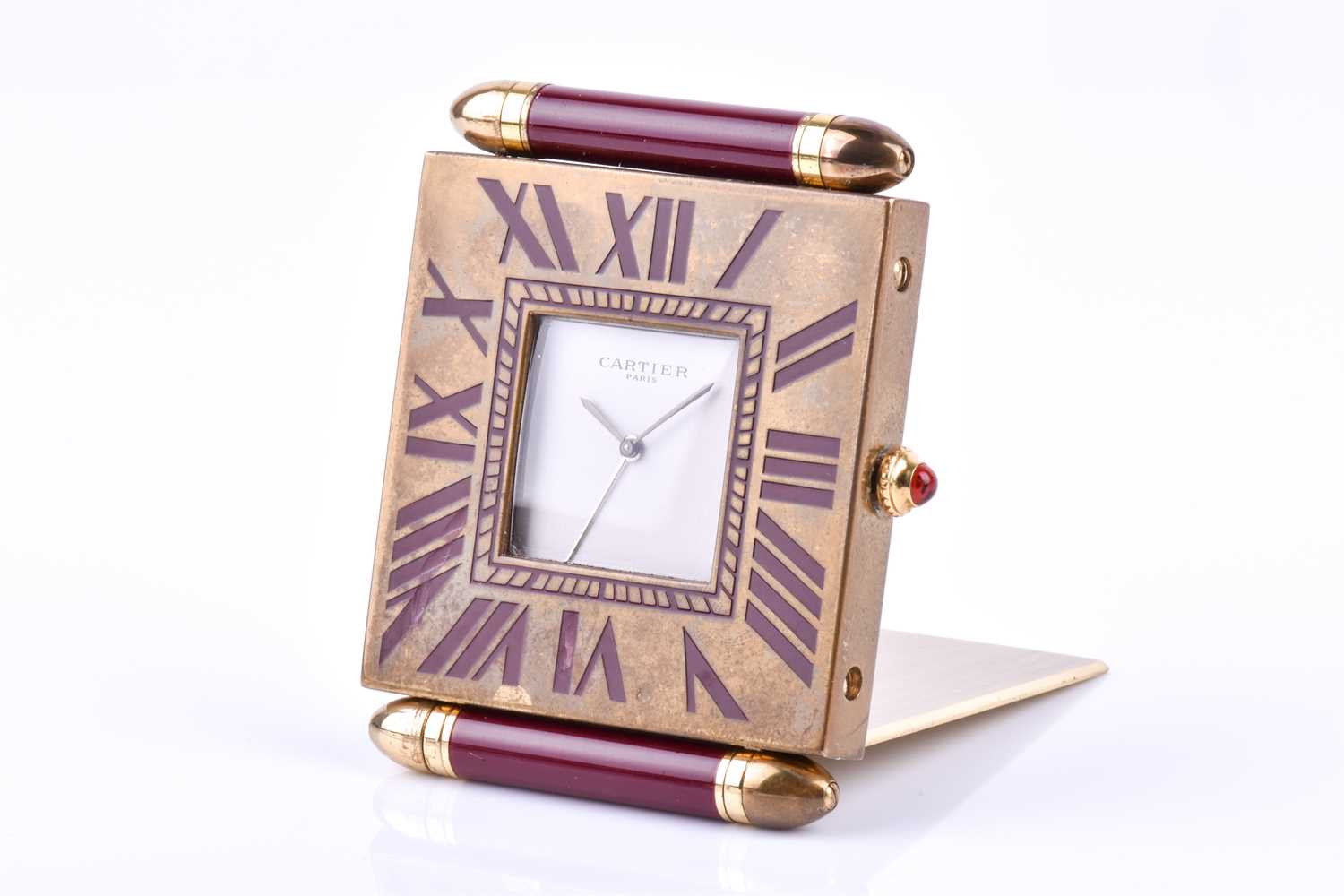 A Cartier travel clock, of square form with gilt metal case with claret lacquered Roman numerals,
