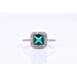 A diamond and emerald ring, set with a square-cut emerald, within a halo border of round brilliant-