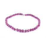 A ruby beaded necklace, comprised of graduated round faceted beads, fastened with a silver clasp,