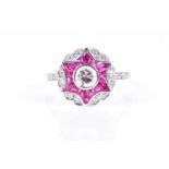 An 18ct white gold, diamond, and ruby ring, in a target style, centred with a round brilliant-cut