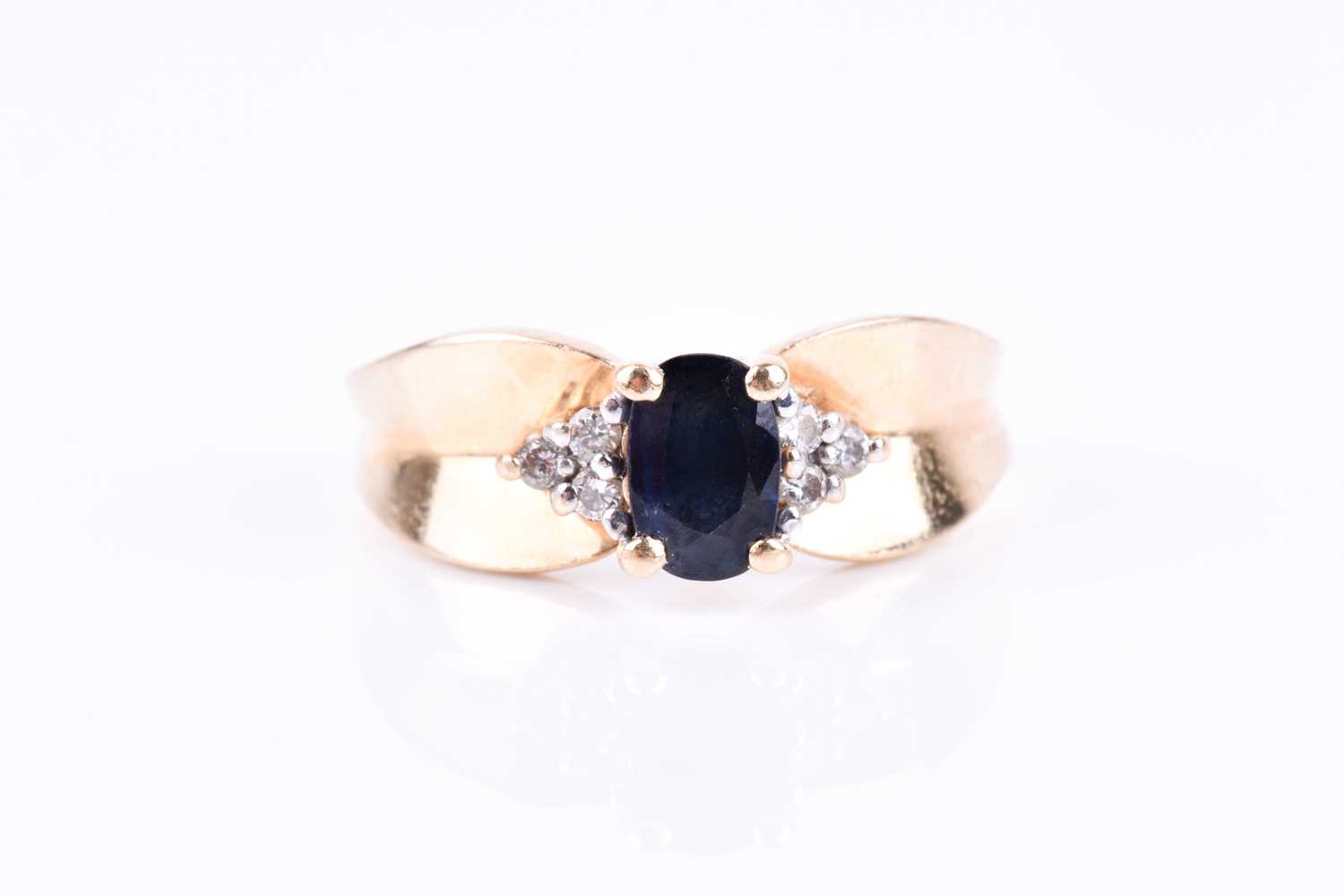A yellow metal and sapphire ring, the pinched mount centred with an oval-cut sapphire and flanked