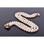 A triple strand graduated pearl necklace, fastened with a yellow metal, pearl, and ruby cluster