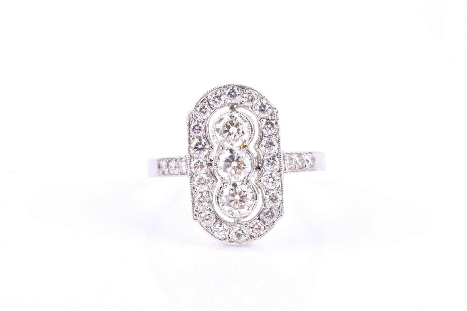 A platinum and diamond ring, the lozenge-shaped mount centred with a row of three round brilliant-